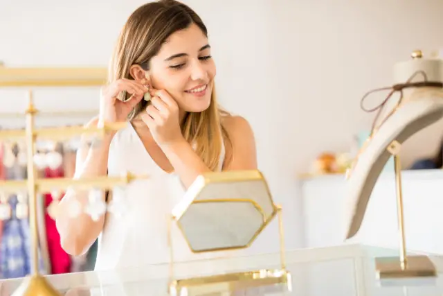 woman putting on earrings